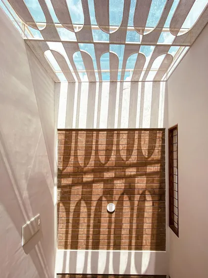 Light is one of our most important materials. Here, a custom-designed geometric skylight casts dramatic patterns across an exposed brick wall, transforming the space and creating a living artwork that changes with the sun.