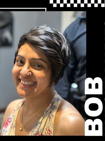 A happy client showing off her new pixie bob haircut. The short, textured style perfectly frames her face and highlights her smile.