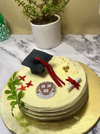Celebrate academic achievements with a custom graduation cake. This one, for a Harvard grad, features a handcrafted graduation cap, a diploma, and the university crest, making for a proud and delicious centerpiece.