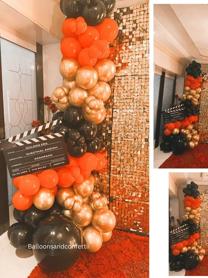 The entrance to the 60th birthday bash, featuring a balloon column in red, black, and gold, and a custom movie clapper board sign.