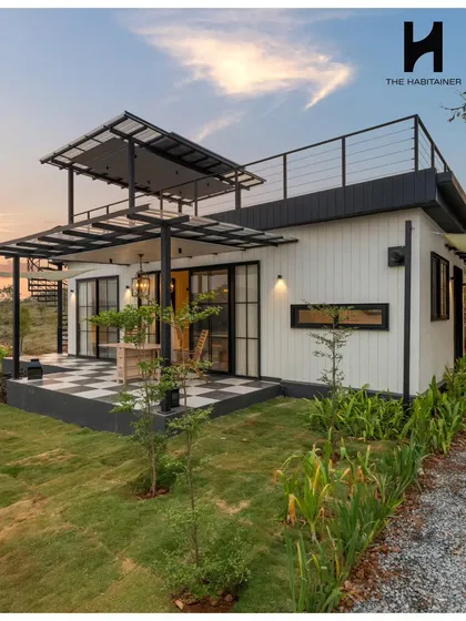 A wider view of the Denkanikotta project, showcasing its modern black-and-white aesthetic. The combination of clean lines, a checkered patio, and surrounding greenery creates a striking visual.