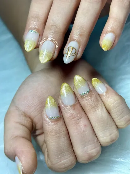 Making engagement nails extra special with personalized initials. For this bride-to-be, we did a beautiful golden ombre with delicate rhinestones and her partner's initials in a stylish monogram.