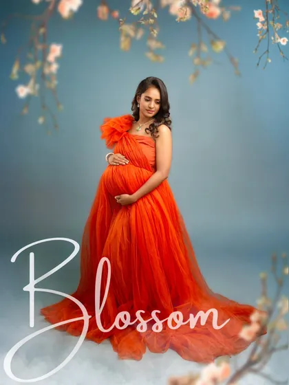 "Blossom" is the perfect word for this image. The mother-to-be, cradling her bump in a vibrant red gown, is the picture of life and beauty in full bloom.