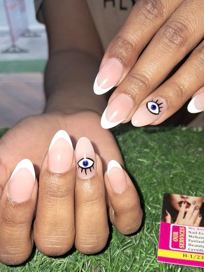 A clean and simple evil eye design paired with a classic white French tip on almond nails.