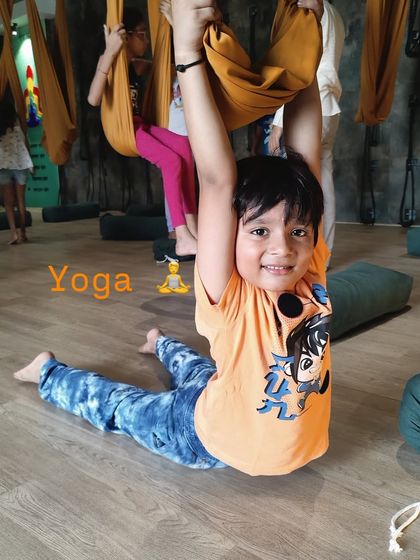 A young boy practices a supported Bhujangasana (Cobra Pose) using an aerial hammock. Even in kids' yoga, props are used to ensure safety and proper form.