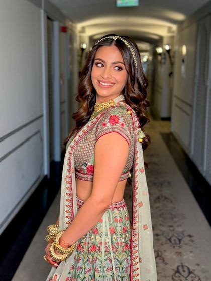 A side profile that showcases the beautiful soft curls in her hair and the flawless finish of her makeup. It's a look that is both romantic and effortlessly chic.