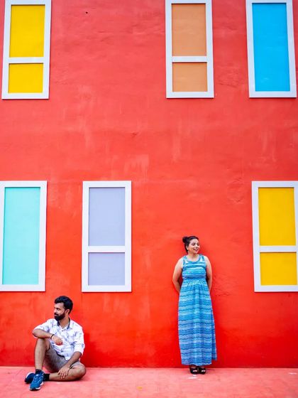A minimalist portrait using a bold red wall with colorful windows as a graphic background. This style is perfect for modern couples who love color and clean lines.