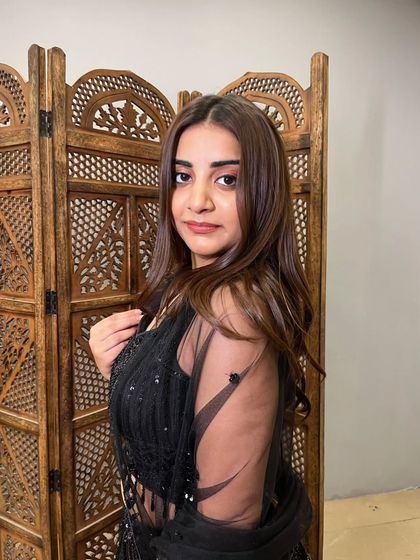 A close-up shot highlighting the model's makeup and the intricate details of the black lehenga's blouse.