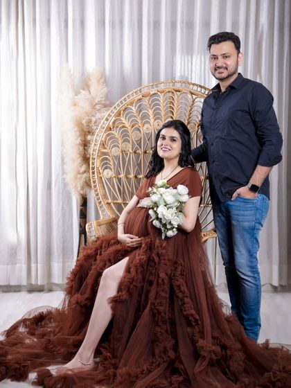 A beautiful portrait of the couple with our boho peacock chair. The mom-to-be holds a white bouquet, adding a touch of classic elegance to the rustic theme.