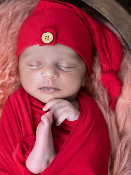 A detailed shot focusing on the baby's tiny features while swaddled in red. We ensure every detail, from the soft wrap to the peaceful expression, is perfect.