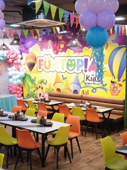 A wider view of the cafe during a mermaid party, showing the ample seating and festive decorations, including hanging lanterns and pennant banners.