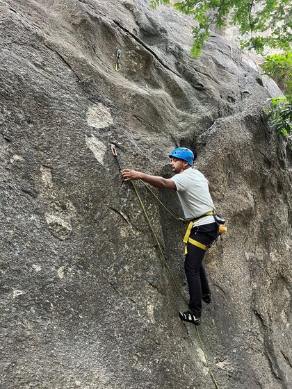 A climber practices clipping the rope into a quickdraw during a lead climbing exercise.