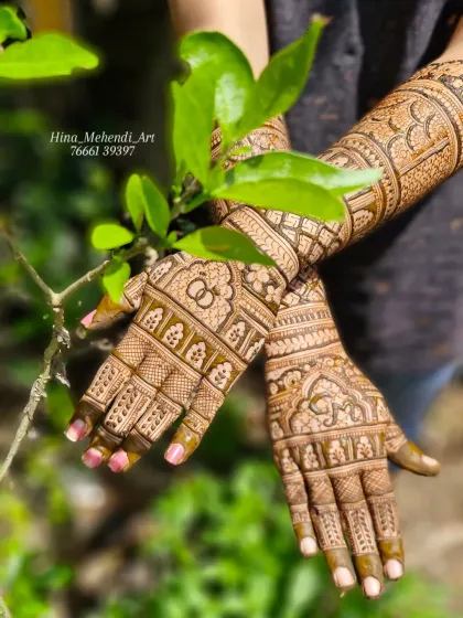 A beautiful example of a traditional engagement mehendi with full coverage. The design includes interlocking rings, geometric patterns, and elephant figures on the wrists.