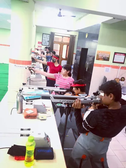A mixed group of young shooters practicing with both pistol and rifle, showing the diversity of talent at the academy.