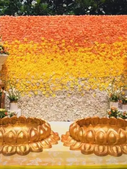 A traditional Haldi ceremony setup featuring a dense wall of yellow, orange, and white marigolds. In the front, two large brass urulis are placed for the rituals, creating a classic and authentic setting for this important pre-wedding function.