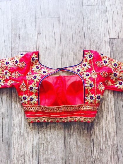 A red blouse with white and gold floral embroidery. The back has a keyhole design, and the work is spread across the entire blouse.