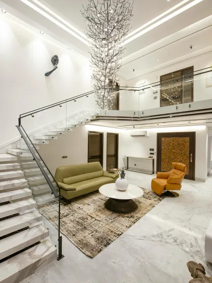 The main living area of a residential project, featuring a floating marble staircase, a statement chandelier, and a comfortable seating arrangement that balances grandeur with intimacy.