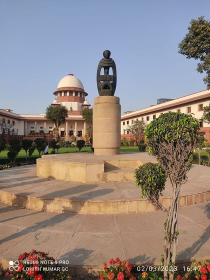 A wider view of the "Mother India" sculpture with the Supreme Court in the background, representing the harmony between justice and the nation.