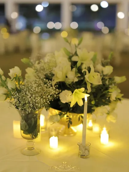 Another beautiful centerpiece, with white lilies and baby's breath illuminated by the warm light of candles, creating a dreamy tablescape.