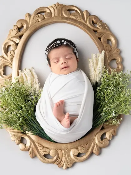 Framed like a precious work of art. Using a vintage-style golden frame and some greenery, we can create a truly unique and elegant portrait of your newborn.