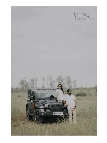 A wide shot of the couple with a Mahindra Thar during their picnic shoot, combining adventure with a romantic theme.