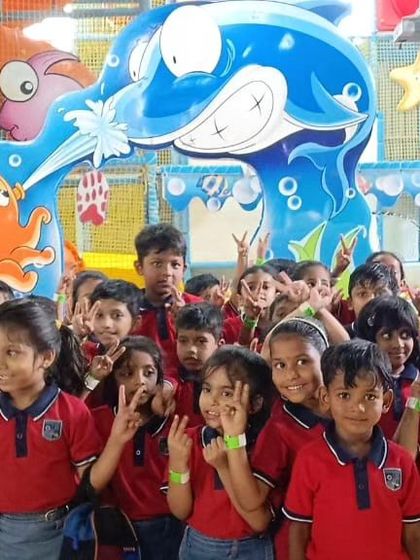 A large group of students posing for a photo during their field trip. The underwater-themed entrance arch at our Bannerghatta center makes for a great photo opportunity.