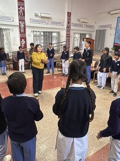 Students stand in a circle for a group activity, fostering a sense of community and collaboration. This setup encourages every child to participate and feel included.