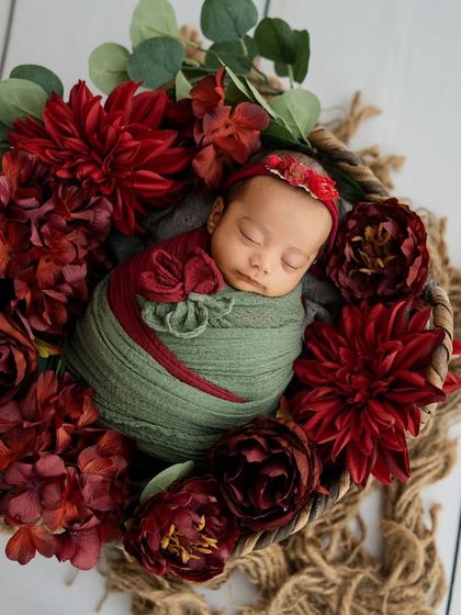 A final shot from this series, capturing the baby's peaceful slumber amidst the vibrant red dahlias. Each floral newborn session is a unique piece of art.