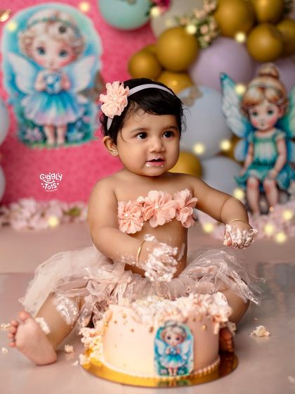 Look at that sweet, cake-covered smile! This little fairy is having a magical time during her first birthday cake smash session.