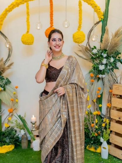 A guest looking radiant in front of our rustic chic Diwali photo backdrop. We used marigolds, pampas grass, and wooden crates to create a warm and festive photo corner.