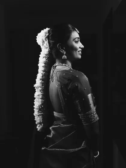 A timeless black and white portrait. This artistic shot beautifully captures the bride's silhouette, the traditional gajra hairstyle, and the serene glow on her face.