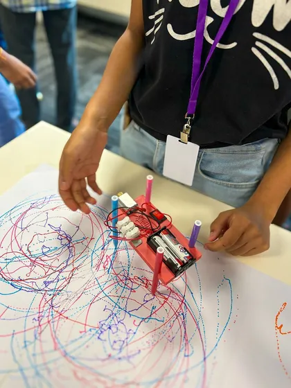 A young creator watches their Art Bot doodle, a moment of pride and discovery.