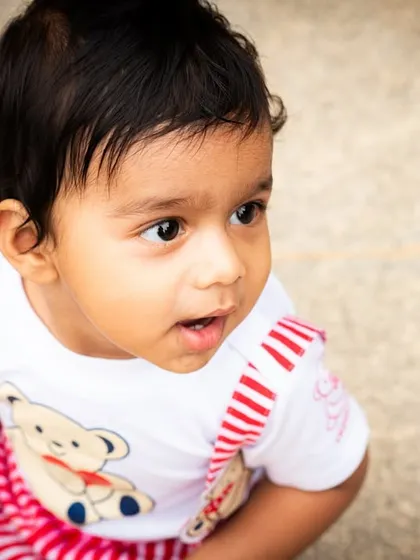 A close-up portrait of a baby outdoors, capturing their innocent and curious gaze.