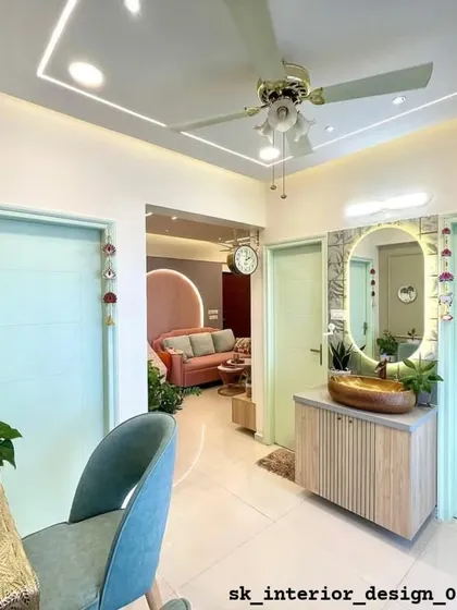 This view shows the connection between the entryway and the living room. A custom vanity with a vessel sink is cleverly placed in the passage, and a glimpse of the pink living room sofa can be seen beyond.