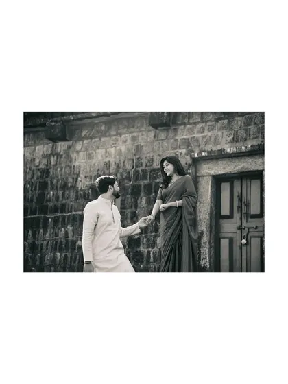 A classic romantic gesture captured in timeless black and white, as the groom-to-be takes his partner's hand.