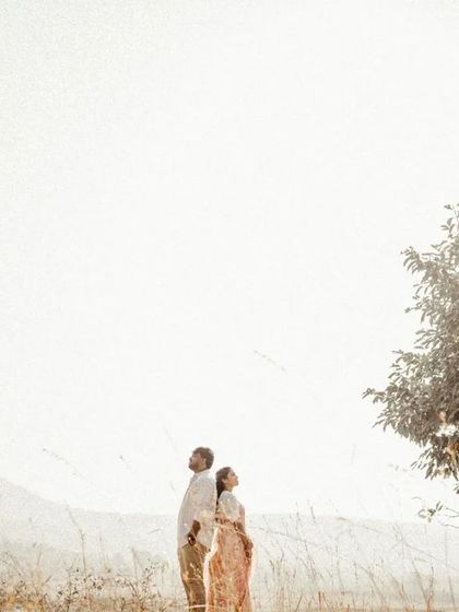 A wide shot of a couple in a golden field with a lone tree, creating a simple yet powerful image of togetherness.