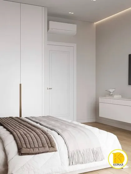 A view of the minimalist TV unit and the seamless, handle-free wardrobe in this modern white bedroom.