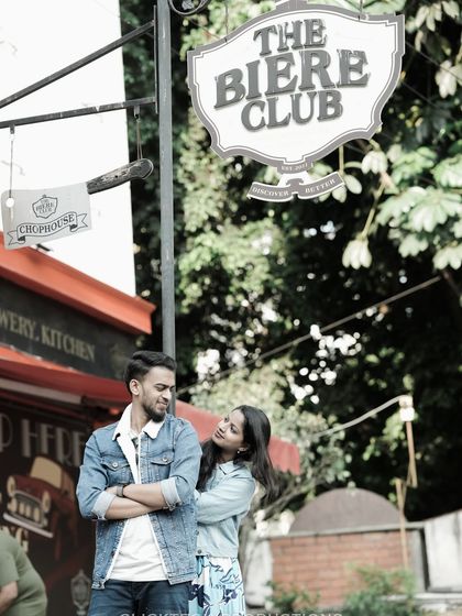A stylish shot of a couple in denim, posing under 'The Biere Club' sign on Church Street, Bangalore.