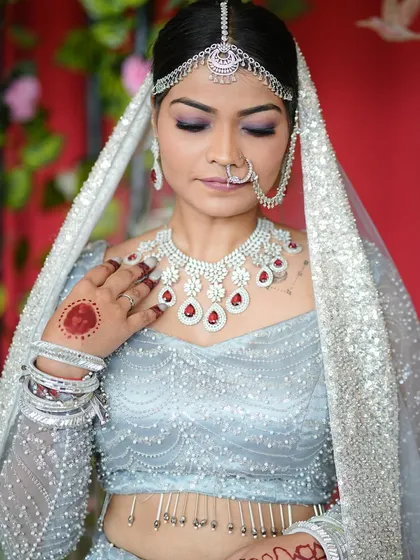 The right nails are essential for a bridal look. To match this bride's stunning silver and red lehenga, we chose a deep red gel polish with a subtle glitter accent. This design perfectly complemented the red stones in her diamond jewelry.