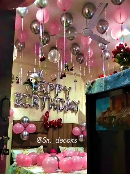 A classic birthday room surprise that never fails to impress. The ceiling is filled with pink and silver balloons with flowing ribbons, paired with 'Happy Birthday' foil letters above the bed for a simple yet joyful celebration.
