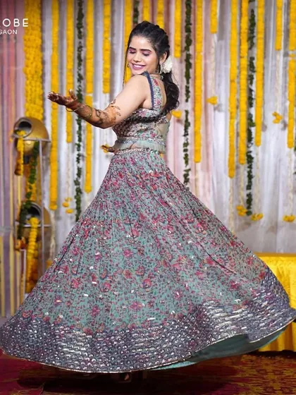 Mehendi vibes, but make it hassle-free. This client is twirling in a beautiful printed lehenga with a contrasting blue dupatta, a perfect choice for a fun-filled Mehendi function.