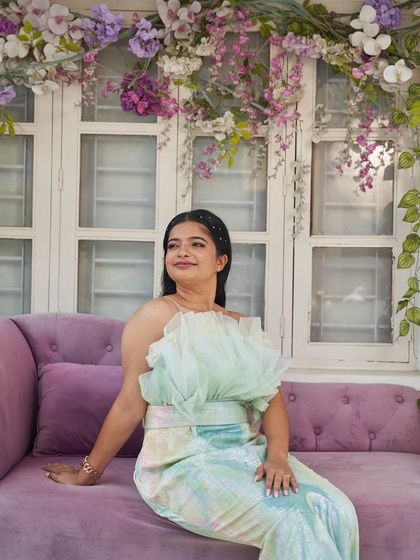 A solo portrait of the bride-to-be in the 'Snowflake' gown, seated on a lilac couch. This shot highlights the gown's unique texture and color.