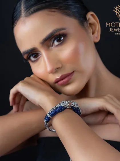 A bold statement of power and elegance. This cuff bracelet features two intricately detailed panther heads, crafted in white gold and covered in blue sapphires.