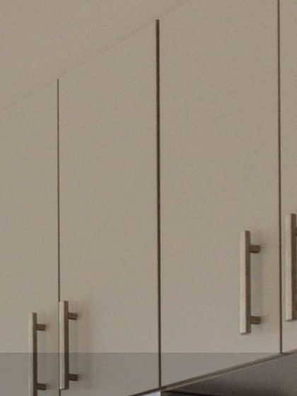 A close-up of simple, flat-panel upper cabinets with modern bar handles. This is a versatile style that works well in many contemporary kitchen designs.