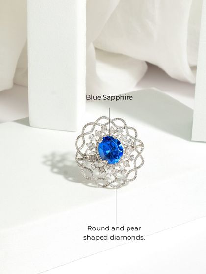 A clean product shot of the Blue Sapphire Cocktail Ring, detailing the central blue sapphire and the intricate, scalloped halo of round and pear-shaped diamonds.