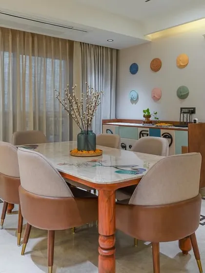 The dining area in our Cleo County project features a beautiful marble-top table with custom inlay work, surrounded by two-toned upholstered chairs. The Greek key pattern on the marble floor border adds a classic, elegant touch to this modern space.