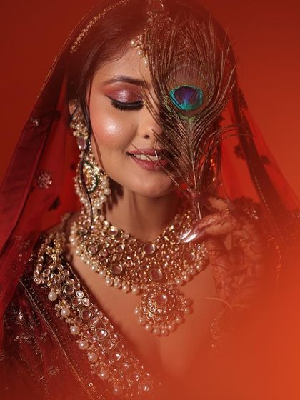 A beautiful, artistic portrait using a peacock feather. The colours of the feather complement the warm tones of the makeup.