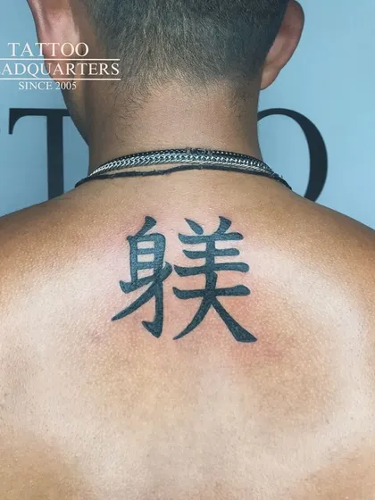 A clean and bold tattoo of Chinese characters on the upper back.