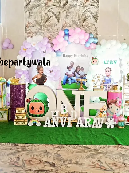A huge Cocomelon party setup on a green turf floor. This creates a fun, park-like feel and includes the Cocomelon school bus and other characters.