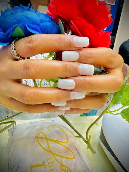 The milky white nails held against colorful flowers, showing their versatility.